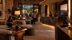 Warm boutique hotel lobby with layered lighting, lounge seating, and a discreet screen near reception